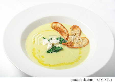 Spinach cream soup with cheese and croutons in white plate. 80345043