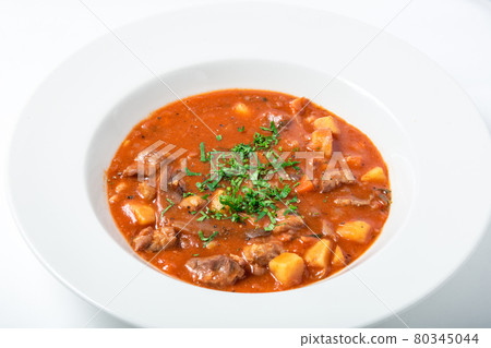 Tomato soup with meat, potatoes, carrots, parsternak in white plate. Tomato soup with meat, potatoes, carrots, parsternak in white plate. 80345044