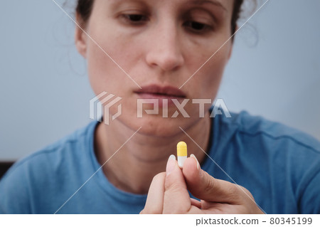 A woman takes a capsule of medicine. Consumption of the drug. Treatment of the disease 80345199