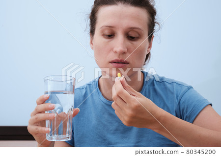 A woman takes a capsule of medicine. Consumption of the drug. Treatment of the disease 80345200