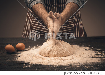 Male hands knead the dough. 80345315