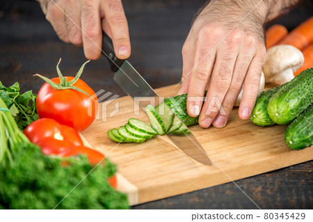 Male hands cutting vegetables for salad Male hands cutting vegetables for salad 80345429