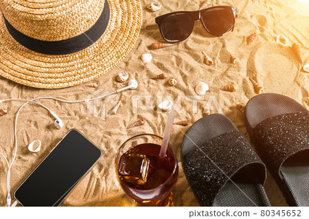 Summer beachwear, flip flops, hat, sunglasses and seashells on sand beach. 80345652