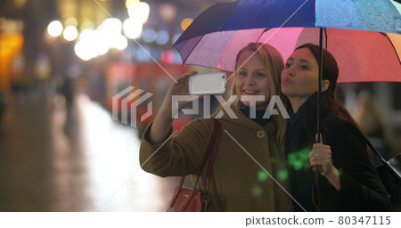 Female friends making selfie under rainbow umbrella Female friends making selfie under rainbow umbrella 80347115