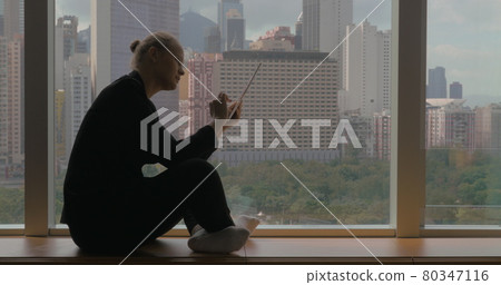 Woman working on business with pad sitting by the window Woman working on business with pad sitting by the window 80347116