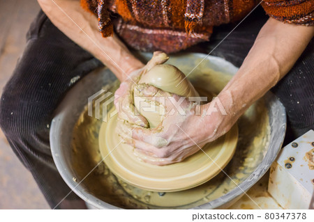 Professional male potter working with clay on pottery wheel 80347378