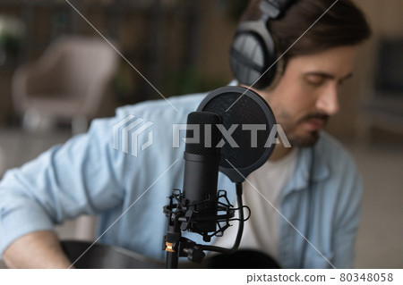 Young man in wired headphones recording own music. Young man in wired headphones recording own music. 80348058