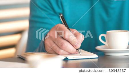 Man using cell phone and making notes Man using cell phone and making notes 80348287