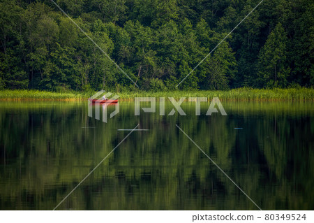 A fisherman in a red boat is fishing in the lake 80349524