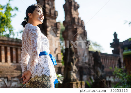 A woman in a traditional costume (Kebaya) at a traditional temple in Bali 80355315