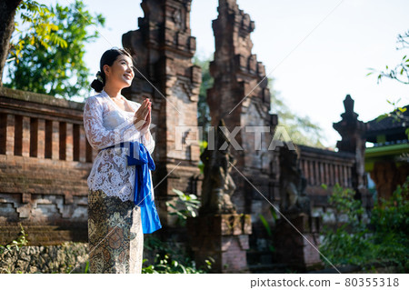 A woman in a traditional costume (Kebaya) at a traditional temple in Bali 80355318