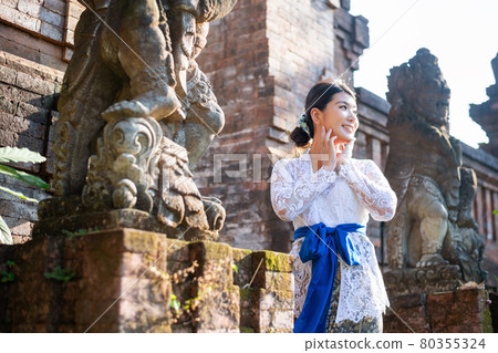 A woman in a traditional costume (Kebaya) at a traditional temple in Bali 80355324
