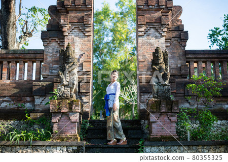 A woman in a traditional costume (Kebaya) at a traditional temple in Bali 80355325