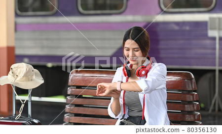 Happy young woman traveler waiting for train at the train station. Happy young woman traveler waiting for train at the train station. 80356130