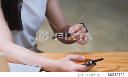 Cropped shot woman hands holding credit card and using smart phone. 80356131