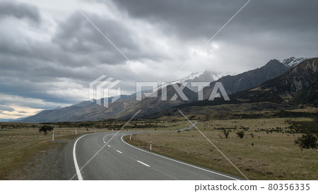 Road leading towards mountains, with cloudy sky. High perspective shot made in Aoraki Mt Cook National Park in New Zealand 80356335