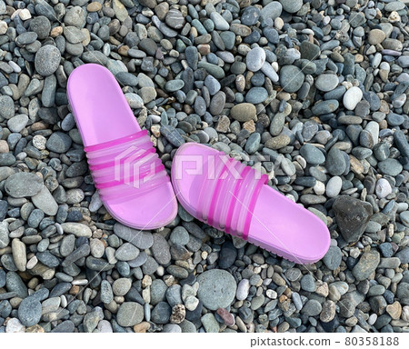 Bright pink slippers are on the pebble beach. Summer walk, sea tourism Bright pink slippers are on the pebble beach. Summer walk, sea tourism 80358188