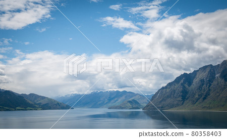 Scenic alpine lake surrounded by mountains shot on sunny day. Location is lake Hawea, New Zealand. Scenic alpine lake surrounded by mountains shot on sunny day. Location is lake Hawea, New Zealand. 80358403