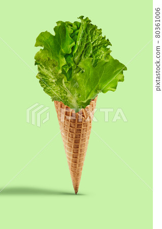 Lettuce leaves in a wafer cone against light green background. Healthy nutrition and seasonal vegetables harvest. Close up, copy space Lettuce leaves in a wafer cone against light green background. Healthy nutrition and seasonal vegetables harvest. Close up, copy space 80361006
