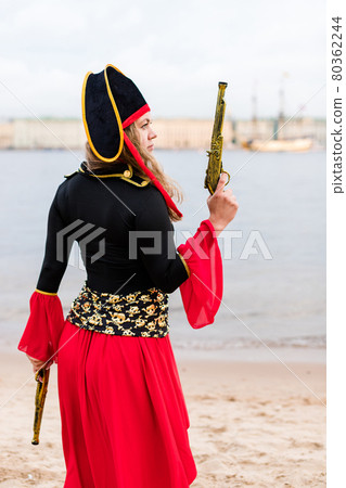 Caucasian woman in pirate costume with firearms. Raised toy gun to the top. 80362244