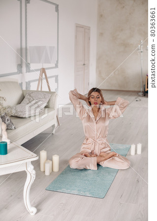 Lady in pajamas practice yoga and sitting in 80363661