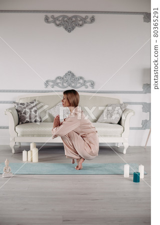 Young lady practicing yoga at home on exercise mat Young lady practicing yoga at home on exercise mat 80365291