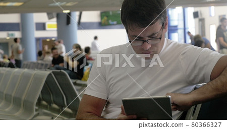Young man working with touch pad at the airport Young man working with touch pad at the airport 80366327