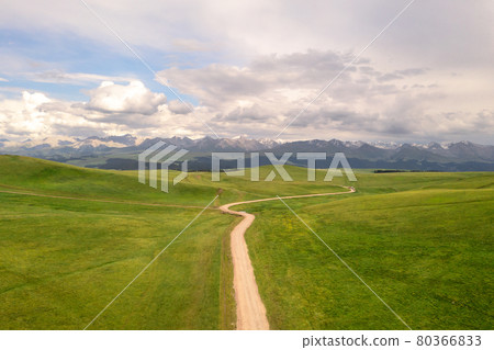 Mountain peaks and grassland are under white clouds. Mountain peaks and grassland are under white clouds. 80366833