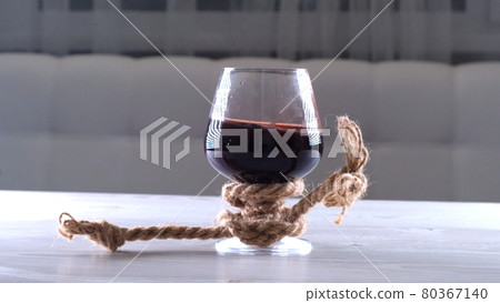 The wine glass is tied with a rope. The concept of alcohol dependence. 80367140
