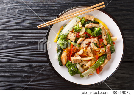 Stir fried of chicken, tofu, bell peppers, carrots, broccoli and bok choy close-up in a plate. horizontal top view 80369072