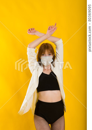 Female strip dancer in yellow studio in protective mask from covid Female strip dancer in yellow studio in protective mask from covid 80369095