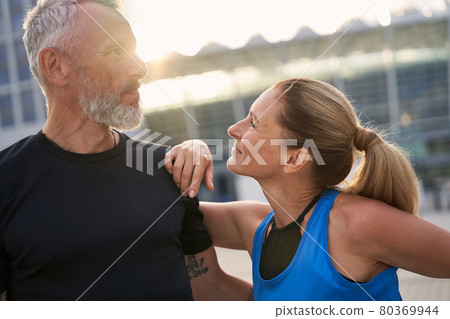 Portrait of loving mature couple, sporty man and woman having morning workout in the city on a summer day Portrait of loving mature couple, sporty man and woman having morning workout in the city on a summer day 80369944
