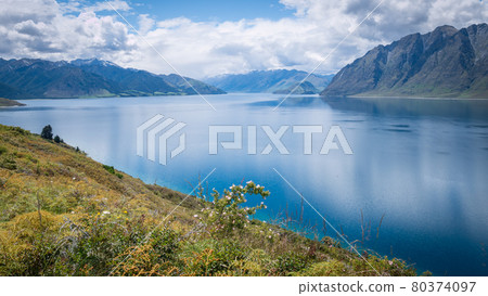 Scenic alpine lake surrounded by mountains shot on sunny day. Location is lake Hawea, New Zealand Scenic alpine lake surrounded by mountains shot on sunny day. Location is lake Hawea, New Zealand 80374097