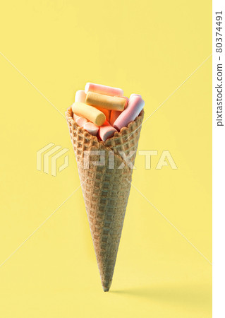 Pink and yellow Marshmallows in waffle cone on light yellow background. Free space for your text Pink and yellow Marshmallows in waffle cone on light yellow background. Free space for your text 80374491