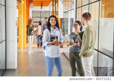 Cheerful brunette lady and her friends standing in hallway Cheerful brunette lady and her friends standing in hallway 80375281
