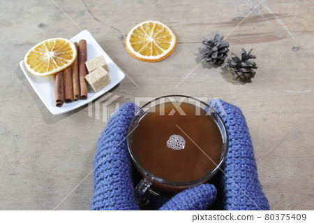 Hands in blue mittens holding a cup of cocoa. Hands in blue mittens holding a cup of cocoa. 80375409