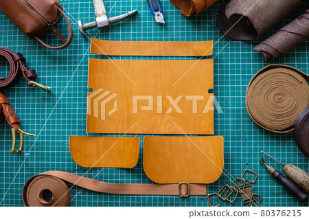 Process cutting scheme of bag with equipment and materials. Male tanner working at leather workshop Process cutting scheme of bag with equipment and materials. Male tanner working at leather workshop 80376215