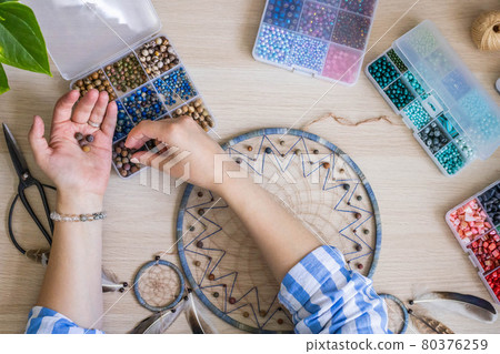 Artistic female hands use colorful beads for creating native tribal Indian amulet dreamcatcher 80376259