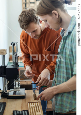 Closeup craftsman hands typing text for branding leather with personal stamp. Creating craft label 80376275