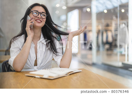 Cheerful business woman talking smartphone smiling having positive emotion at modern shopping mall 80376346