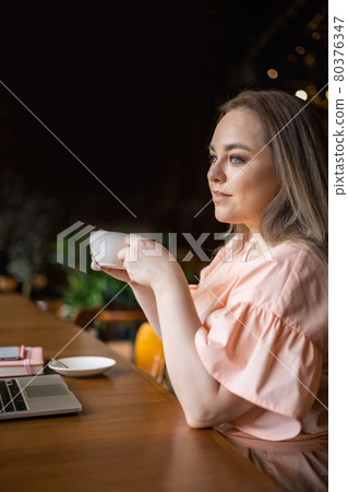 Pensive elegant plus size business woman drinking coffee working at cafe use laptop enjoying break Pensive elegant plus size business woman drinking coffee working at cafe use laptop enjoying break 80376347