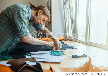 Craftsman drawing scheme lining for bag on tissue creating leatherwork at studio leather workshop 80376387