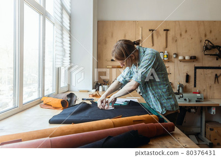 Craftsman drawing scheme lining for bag on tissue creating leatherwork at studio leather workshop 80376431
