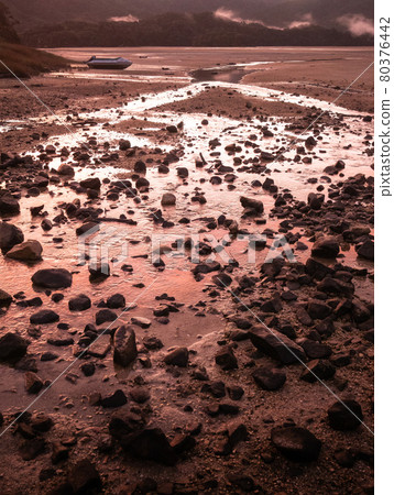 Crimson sunset in tropical inlet bay with deserted boat in frame. Portrait shot made in Abel Tasman National Park, New Zealand 80376442