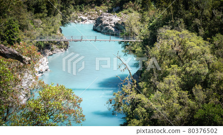 River gorge with turquoise waters and swing bridge leading above it. Landscape shot made at Hokitika gorge, West Coast, New Zealand 80376502