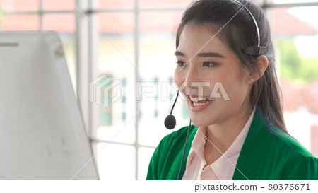 Businesswoman wearing headset working actively in office 80376671