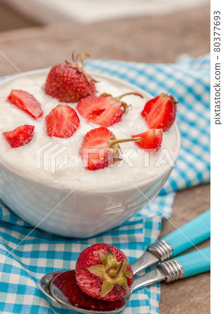 In a cup of yogurt and fresh strawberries, on a blue spoon towel 80377693