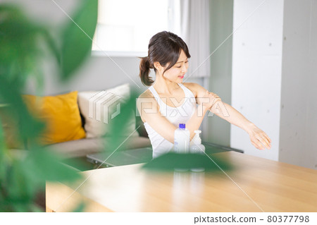 Young woman applying cream to her arms 80377798