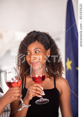 African American woman in a meeting having a glass of red wine African American woman in a meeting having a glass of red wine 80385620