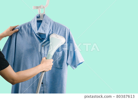 A woman ironing clothes with Steam iron green background 80387613